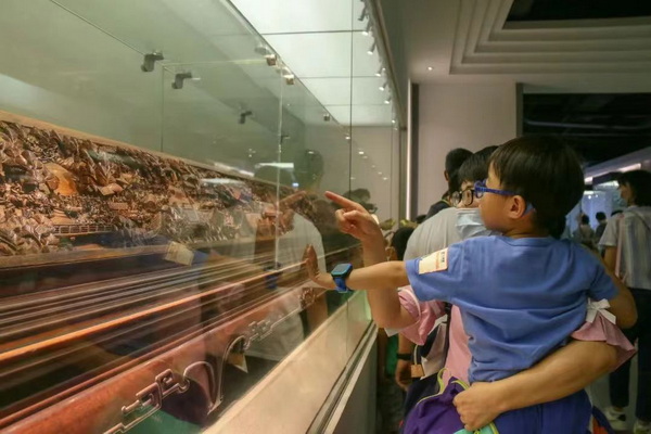 一对母子正在观赏黄花梨清明上河图木雕作品 一对母子正在观赏黄花梨清明上河图木雕作品